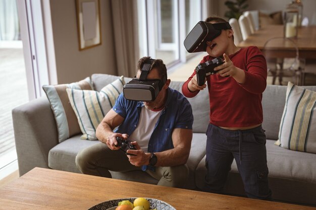 Foto padre e figlio caucasici che indossano cuffie vr giocano ai videogiochi a casa