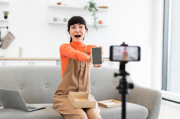 Caucasian female blogger unboxing smartphone during live online session