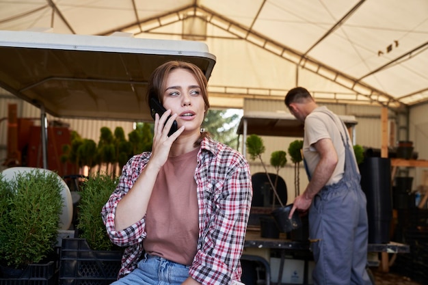 Caucasian female botanist using mobile phone in the greenhouse