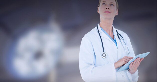 Caucasian female doctor using digital tablet against surgical light in background