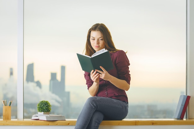 Caucasian female on windowsill reading book