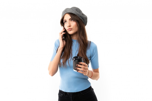 Caucasian female with cap drinks coffee and call to the phone, picture isolated on white background