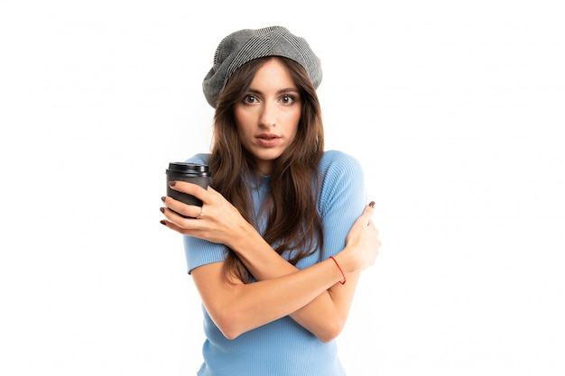 Caucasian female with cap drinks coffee and is freezing, picture isolated on white background