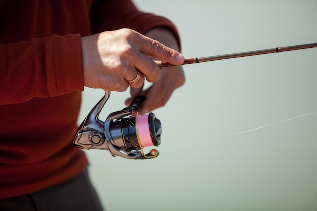 Caucasian fisherman holds a spinning rod in his hands, close-up. Sport fishing. a spinning rod