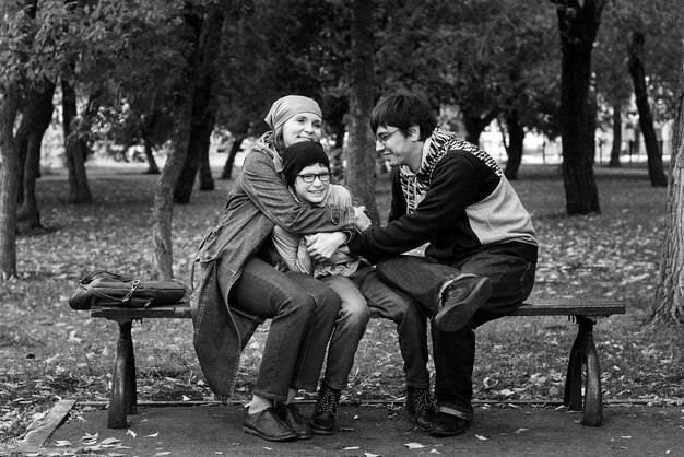 Caucasian fun family dad mom and their son are sitting on a bench in the Park in autumn