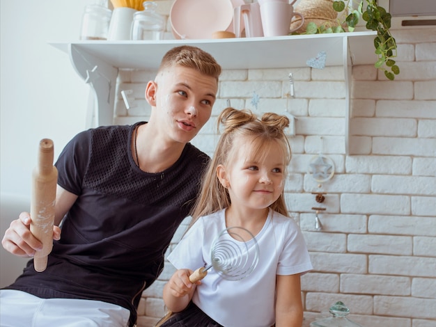 caucasian funny cute siblings in kitchen  little girl with older brother baking in kitchen