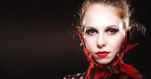Photo caucasian ginger model with fantasy feathers make up