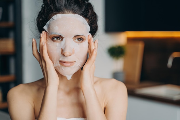 Photo caucasian girl applies mask sheet after bathing vitamin nourishing and nutrition face mask