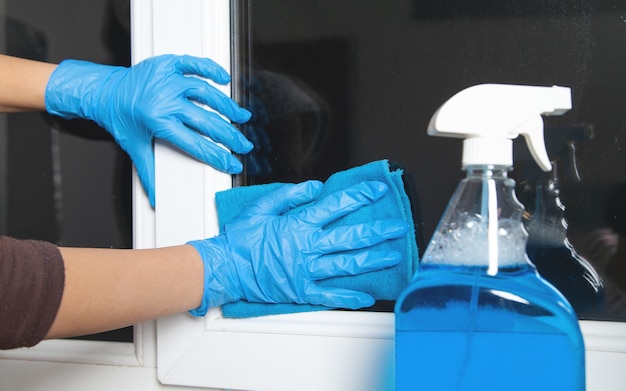 Caucasian girl cleans window at home.