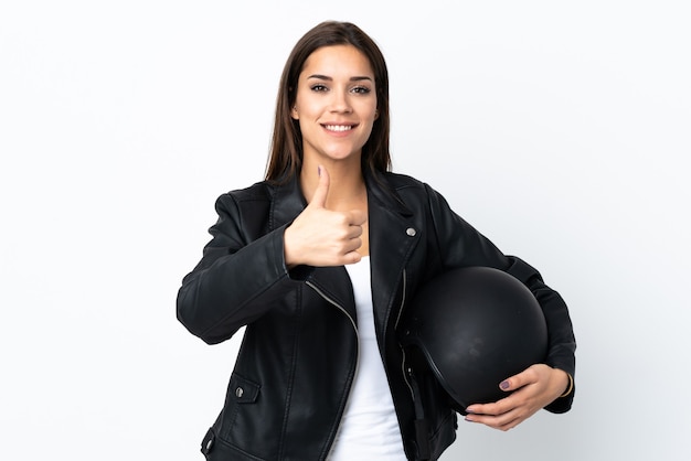 Кавказская девушка держит мотоциклетный шлем на белом и показывает палец вверх