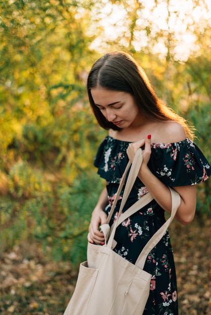 Caucasian girl holds linen shopper on sunset outdoors