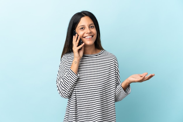 Caucasian girl isolated on blue background keeping a conversation with the mobile phone with someone