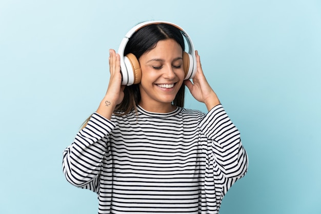 Caucasian girl isolated on blue listening music