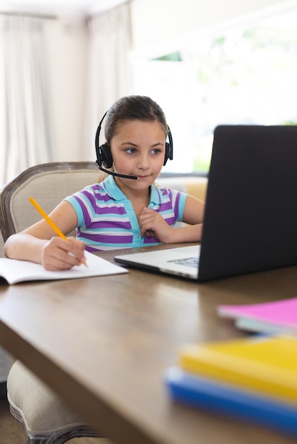 Caucasian girl learning and using laptop and headphones in living room