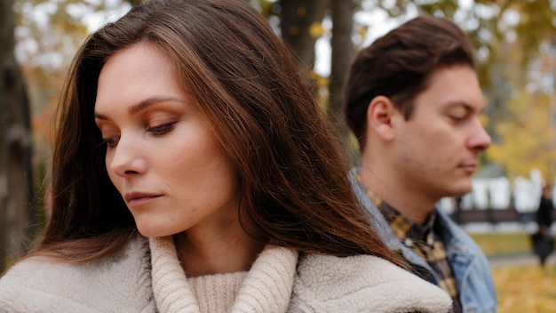 Caucasian girl offended by male lover on background young family couple standing outdoors ignoring