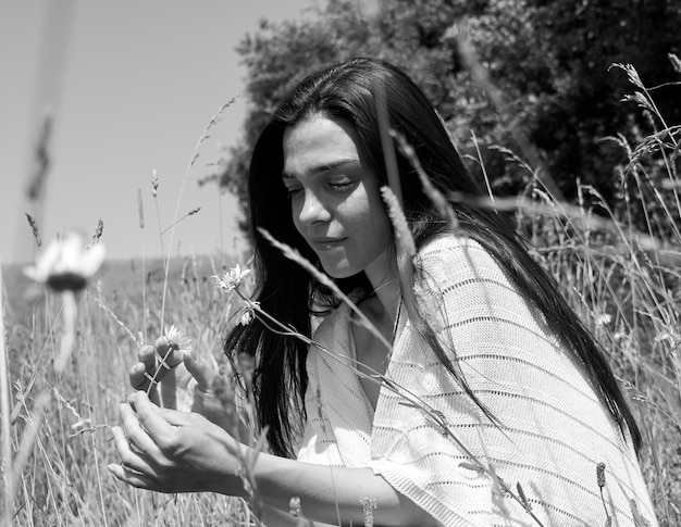 Photo caucasian girl playing with a flower in the field with a white top