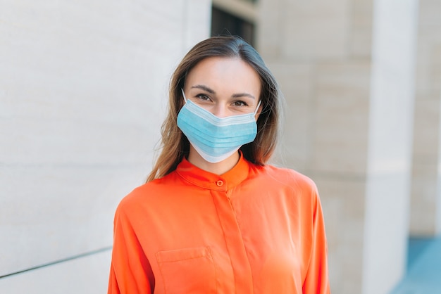 Caucasian girl smiling and wearing a medical mask walking in the summer city