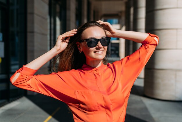 Caucasian girl in sunglasses and casual clothes rejoices in the sunny weather.