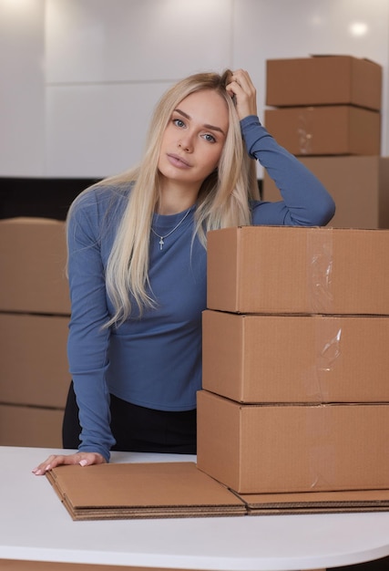 Фото Кавказская девушка заклеивает коробки для переезда в новую квартиру