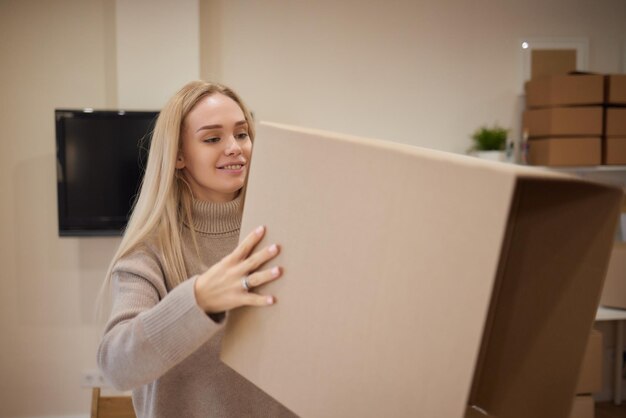 Caucasian girl taping boxes for moving in new apartment