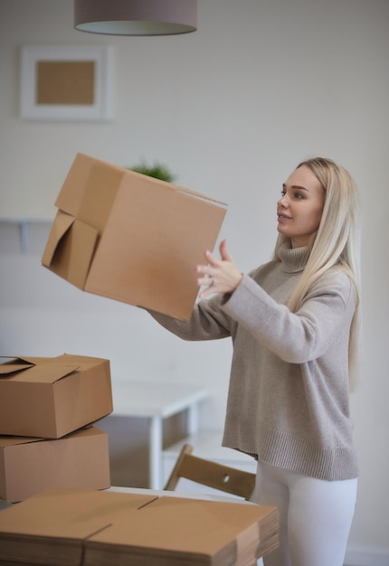 caucasian girl taping boxes for moving in new apartment