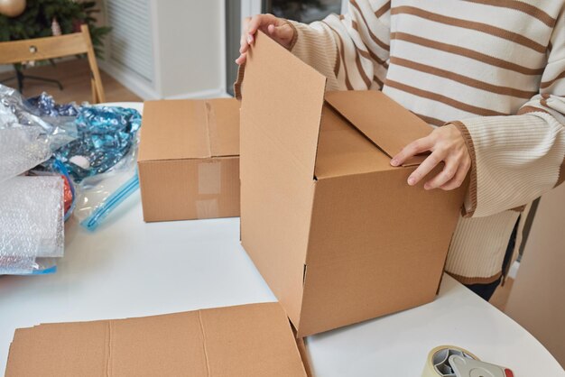 Caucasian girl taping boxes for moving in new apartment