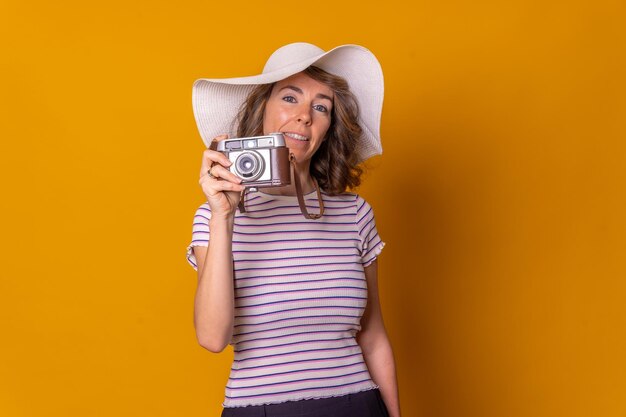 Caucasian girl in tourist concept on a yellow background with hat and camera