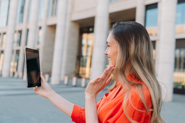 Caucasian girl using tablet and talking on video chat and saying hello.