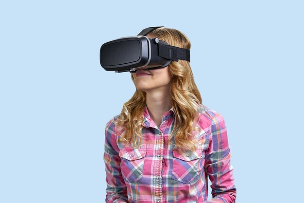 Кавказская девушка, использующая гарнитуру виртуальной реальности на синем фоне, будущие технологии и инновации