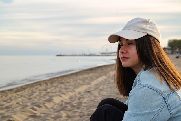 Foto ragazza caucasica con i capelli lunghi e il berretto che guarda serenamente all'orizzonte