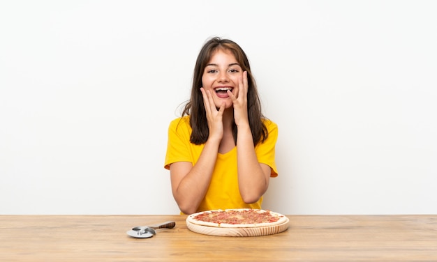 Ragazza caucasica con una pizza con espressione facciale a sorpresa