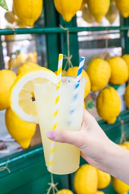 Caucasian hand with healthy fresh lemonade during summer lemons background