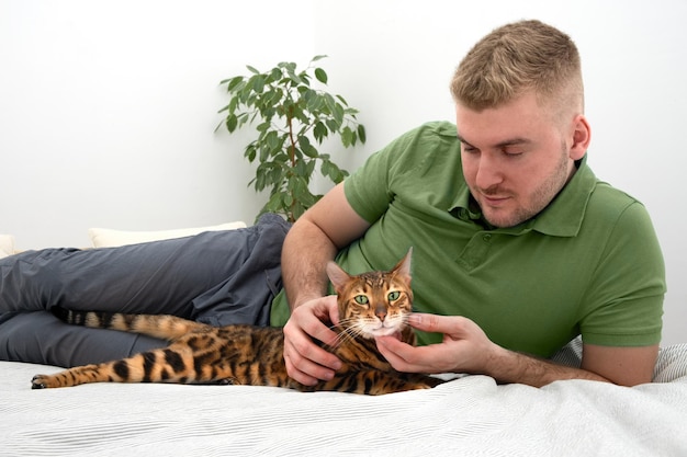 Caucasian handsome blond bearded man caressingstroking beautiful bengal catPeople and pet relationshiplovecareAnimal and person friendshipRelaxing at home conceptLifestyle photo