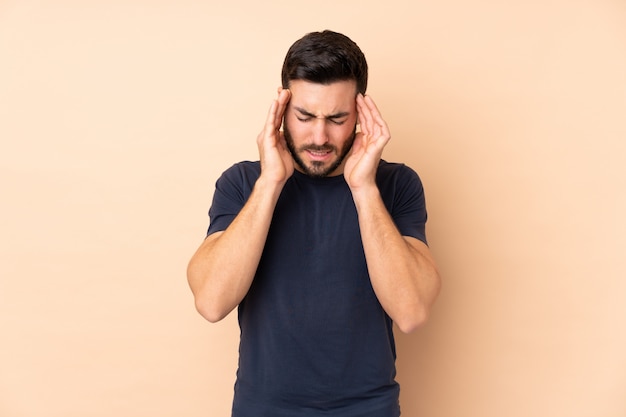 Caucasian handsome man on beige wall with headache