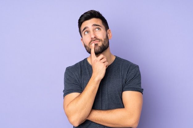 Caucasian handsome man having doubts while looking up isolated