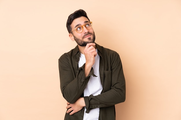 Caucasian handsome man isolated on beige wall and looking up