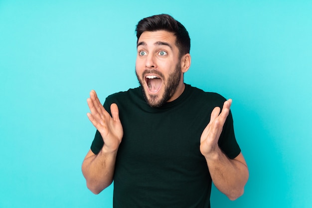 Photo caucasian handsome man isolated on blue wall with surprise facial expression
