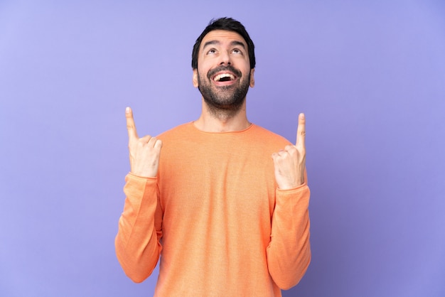 Caucasian handsome man over isolated purple surprised and pointing up