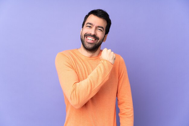 Caucasian handsome man over isolated purple wall celebrating a victory