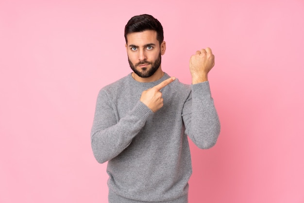 Caucasian handsome man over isolated wall making the gesture of being late