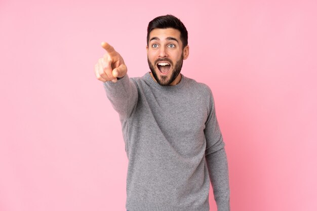 Caucasian handsome man over isolated wall pointing away