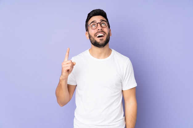 Caucasian handsome man over isolated wall pointing up and surprised