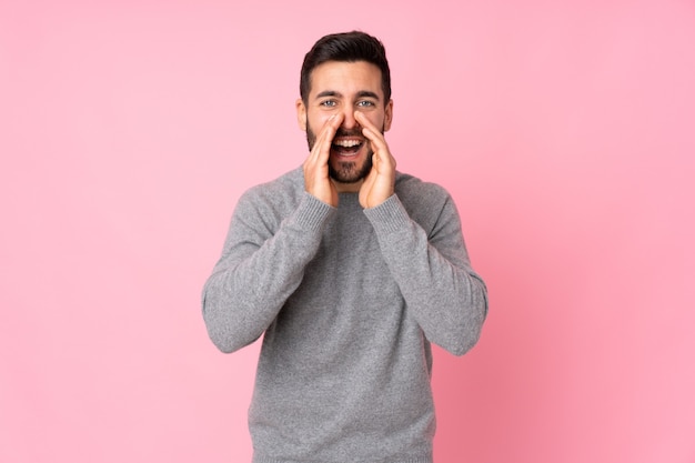 Caucasian handsome man over isolated wall shouting and announcing something