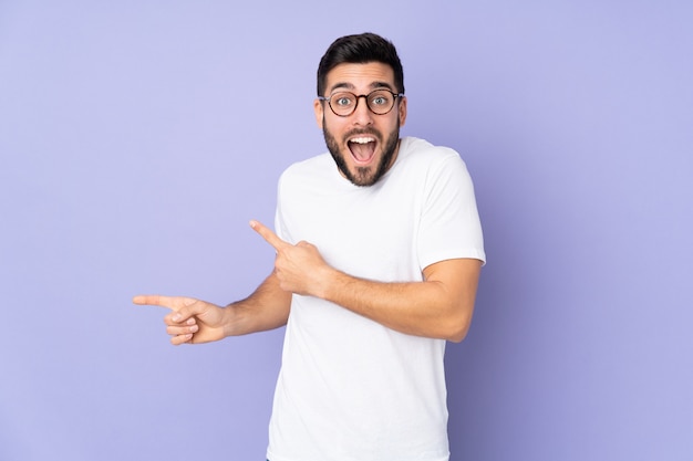 Caucasian handsome man over isolated wall surprised and pointing side