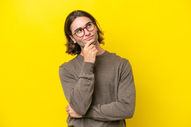 Caucasian handsome man isolated on yellow background and looking up