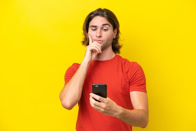 Caucasian handsome man isolated on yellow background thinking and sending a message