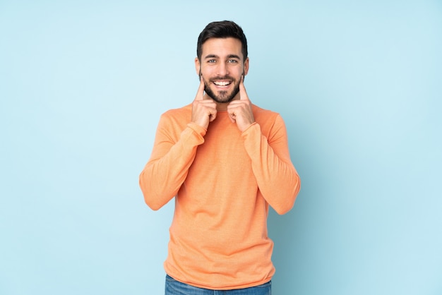 Uomo bello caucasico che sorride con un'espressione felice e piacevole sopra la parete blu