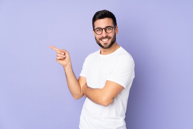 Caucasian handsome man over wall pointing finger to the side