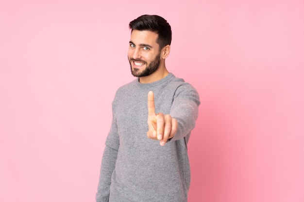 Caucasian handsome man over wall showing and lifting a finger