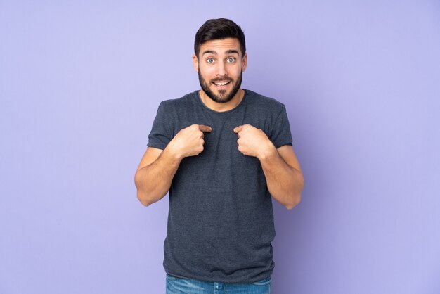 Caucasian handsome man with surprise facial expression over isolated purple wall